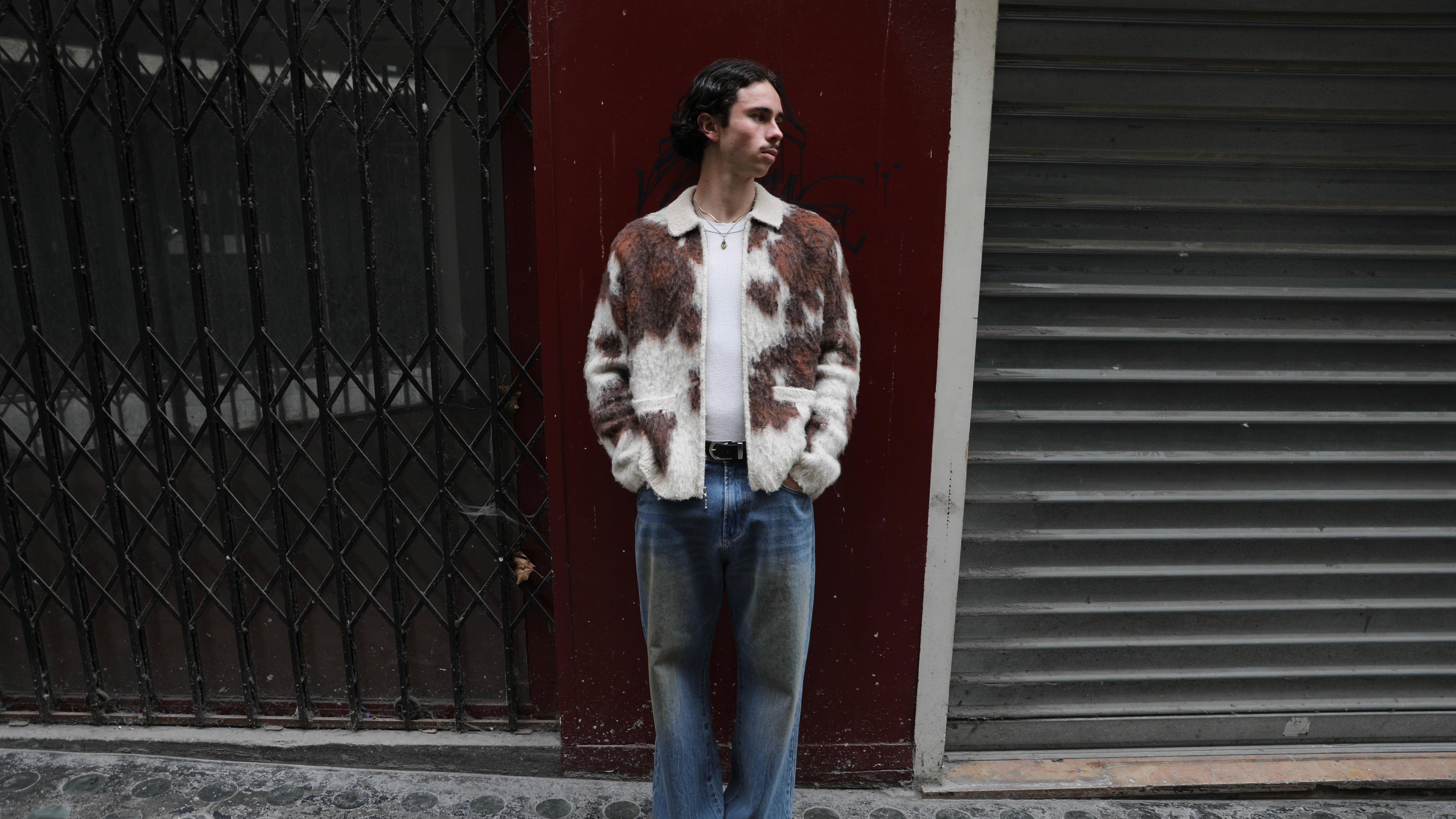 A grey and burgundy OBEY sweater with a white collar and two white buttons. The black logo is centered on the chest. Background is cracked concrete.