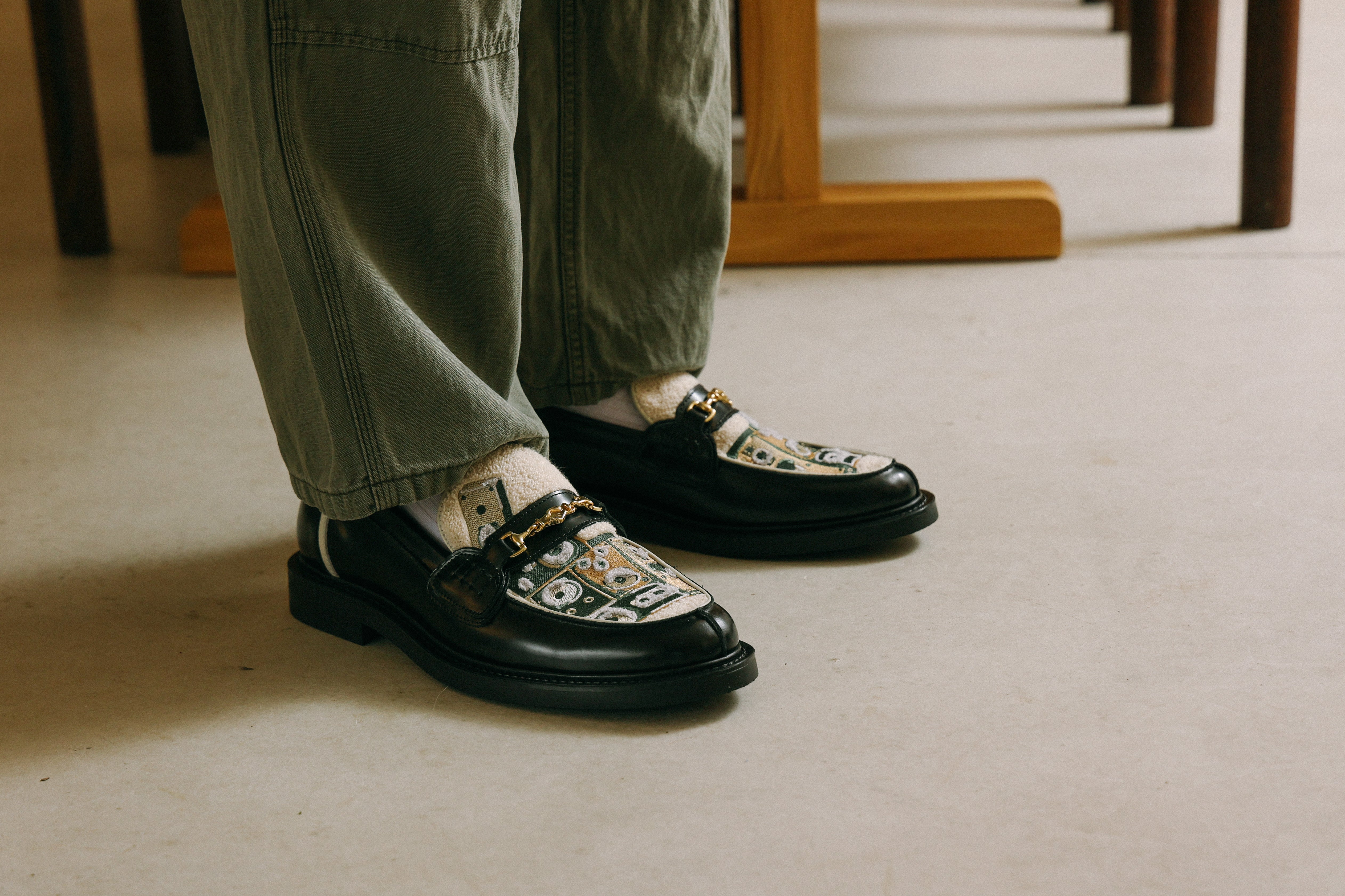 Two pairs of low loafers: one black with silver details, the other orange-brown with silver details.